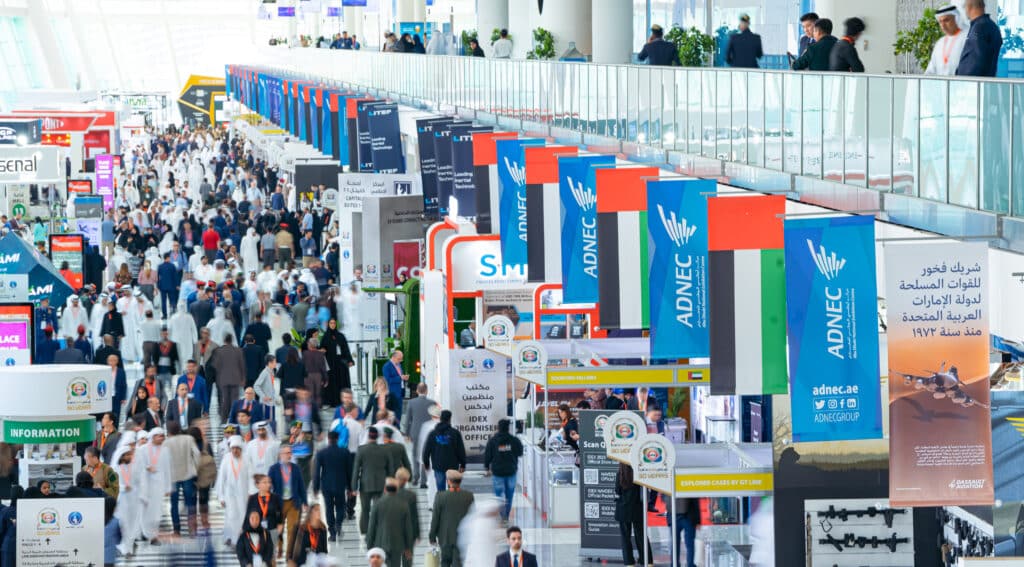 IDEX 2023 event held at the ADNEC Centre Abu Dhabi showing busy exhibition stall and people networking.